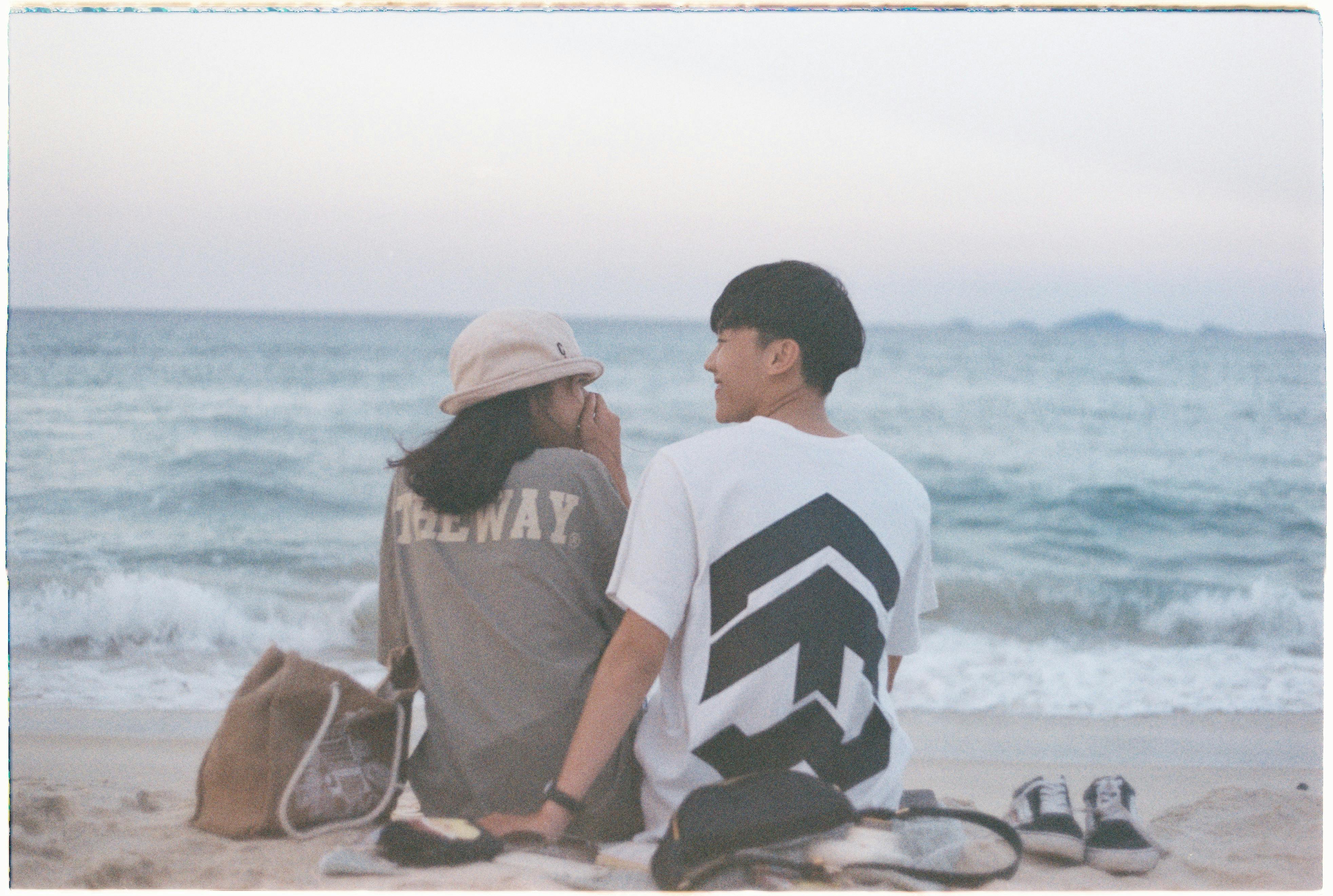 An Asian couple enjoys a serene beach evening in Cam Ranh, Vietnam, facing the sea.