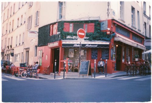 Free A quaint Paris bistro on a bustling street corner with outdoor seating and vibrant architecture. Stock Photo