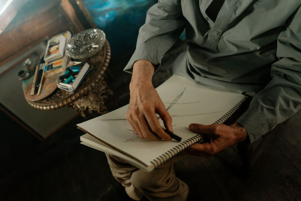 close up of an artist sketching with charcoal on paper in a cozy indoo