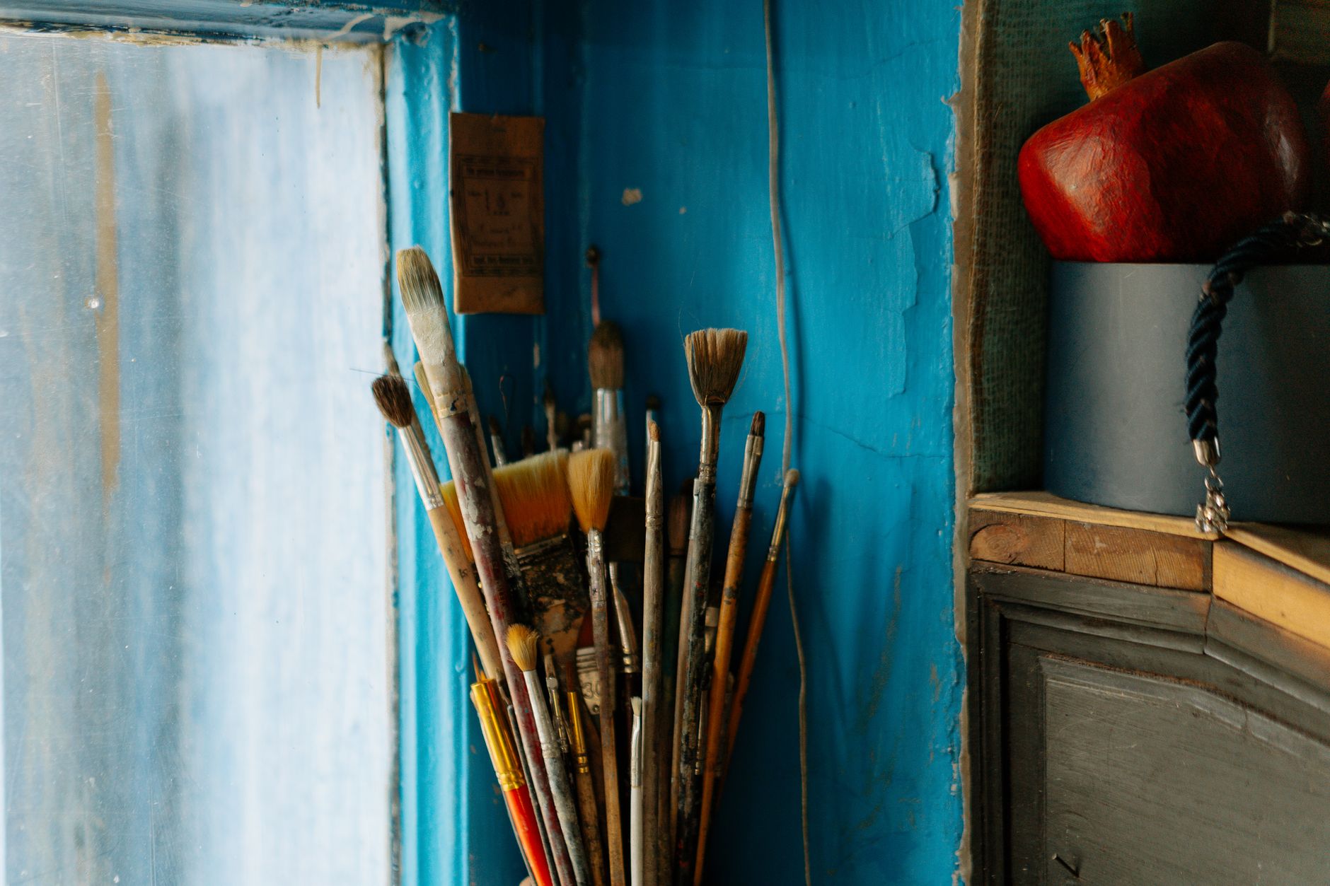 A rustic collection of paintbrushes against a textured blue wall, capturing artistic inspiration.