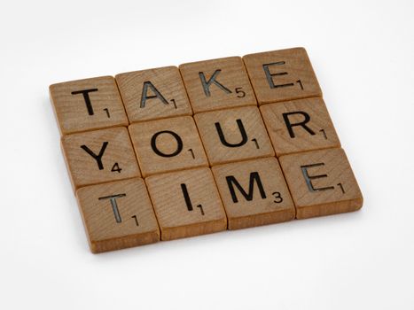 Wooden Scrabble tiles spelling 'Take Your Time' encouraging patience and reflection.