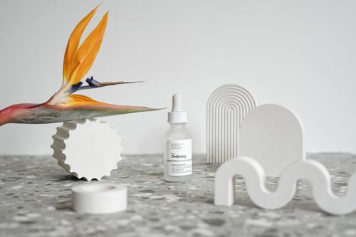 Free Modern still life featuring a cosmetic serum surrounded by abstract shapes and a Bird of Paradise flower. Stock Photo