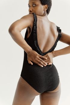 Portrait of a woman in a stylish black swimsuit, showcasing elegance and fashion.