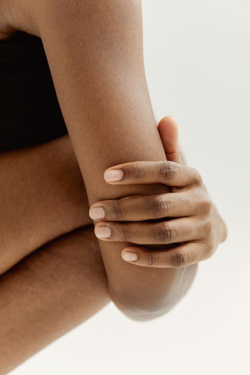 Free A close-up shot of a hand resting on an arm, captured in a minimalist and neutral tone. Stock Photo