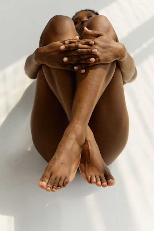 Free Minimalist portrait of a woman with legs crossed, capturing elegance and sensuality. Stock Photo