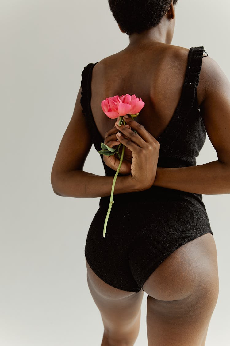 Woman Holding A Pink Flower Behind Her Back