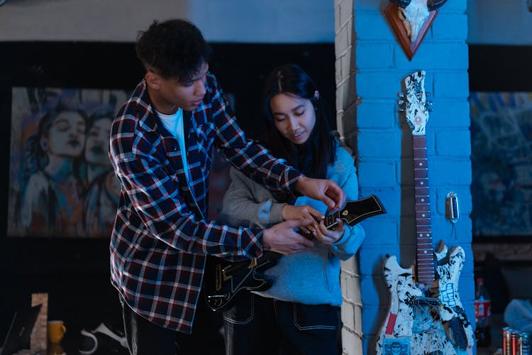 Man Teaching A Woman How To Play Guitar