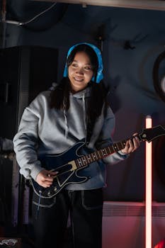 Asian woman enjoying a music video game with a guitar controller in a casual indoor setting.