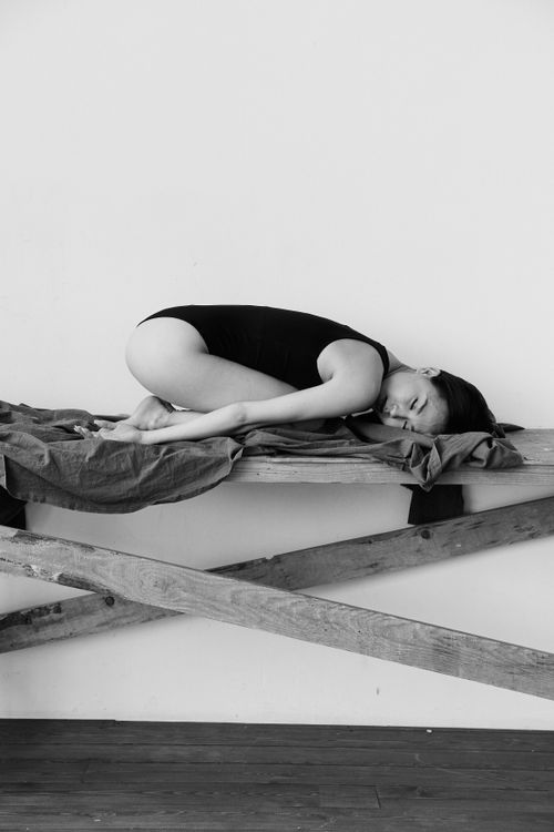 Free Elegant black and white photo of a woman in a bodysuit lying on a bench, showcasing minimalist art. Stock Photo