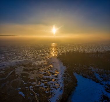 Aerial view of the Minnesota coastline at sunrise with frozen waters and golden reflections.