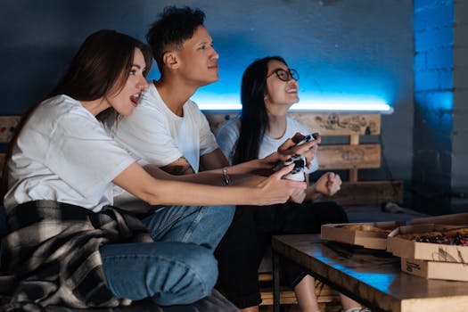Three friends play video games together indoors, enjoying pizza and fun times.