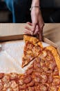 Person Holding Pizza on Brown Box