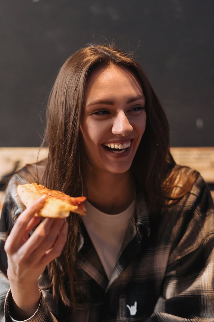 A Woman Holding A Slice Of Pizza 