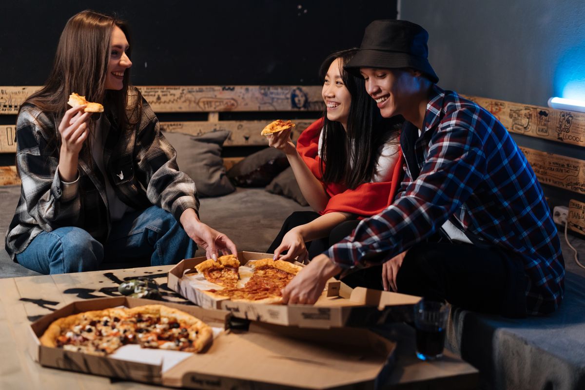 Group of friends enjoying pizza and laughter indoors