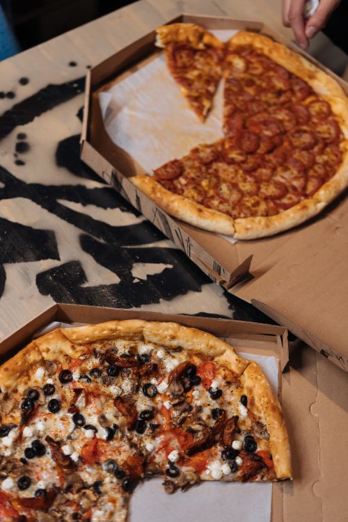 Free A top view of pepperoni and vegetarian pizzas in boxes on a wooden table, perfect for delivery or fast food themes. Stock Photo