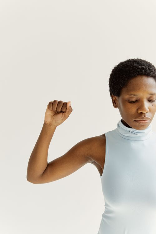 Free Portrait of a confident woman in light blue sleeveless turtleneck against a white background. Stock Photo