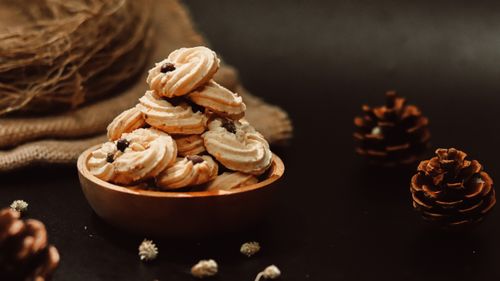 Free A cozy, rustic setup with cookies and pine cones on a dark background, embodying a warm autumn aesthetic. Stock Photo