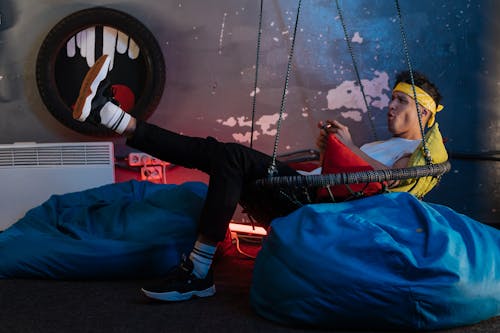 Man playing Games while sitting on a Hanging Chair 