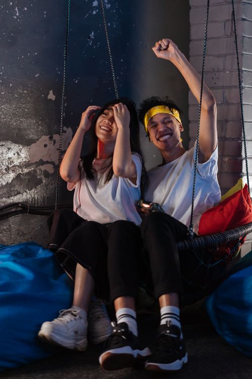 Free A happy young couple smiling and having fun on a cozy indoor swing. Stock Photo