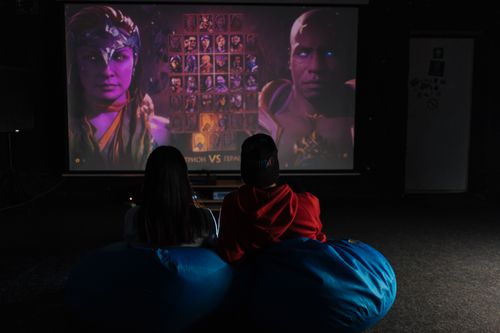 Free Two friends enjoying a video game session on a projector screen, immersed in gameplay. Stock Photo