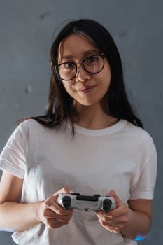 A young woman with glasses holding a game controller, engaged in gaming indoors.