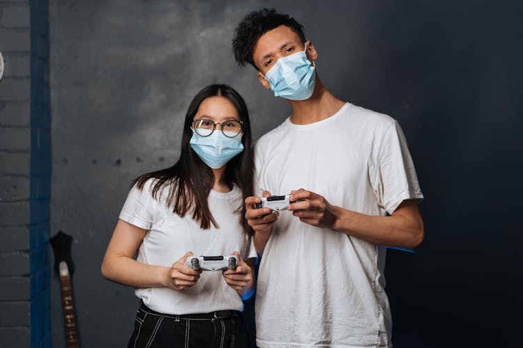 A Man And A Woman Holding Playstation Controllers