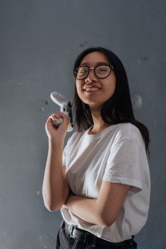 Portrait of a cheerful young woman holding a game controller against a gray background.