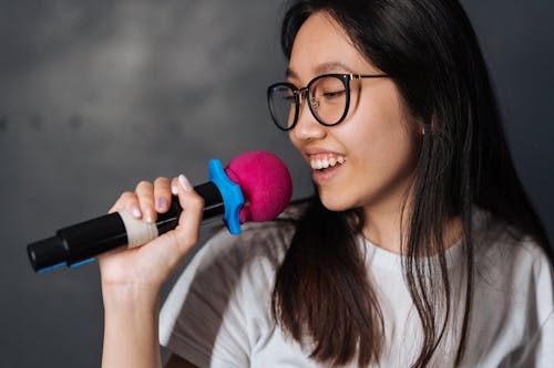 Free Young Woman in Black Eyeglasses using a Microphone  Stock Photo