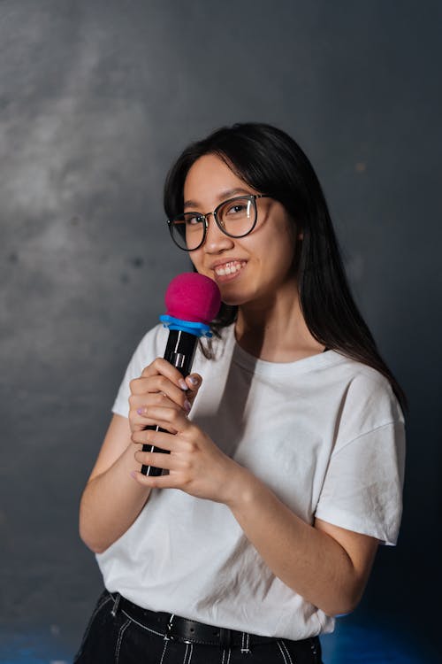 Free Young Woman in Black Eyeglasses holding a Microphone Stock Photo