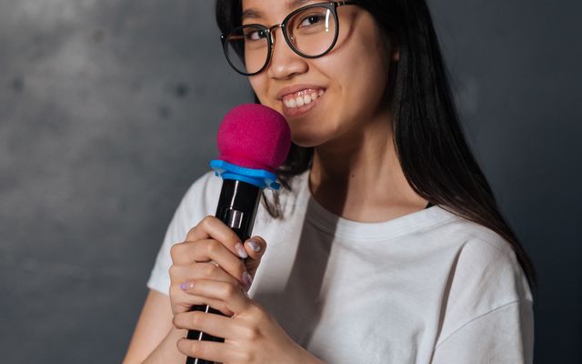 A smiling young woman holding a karaoke mic