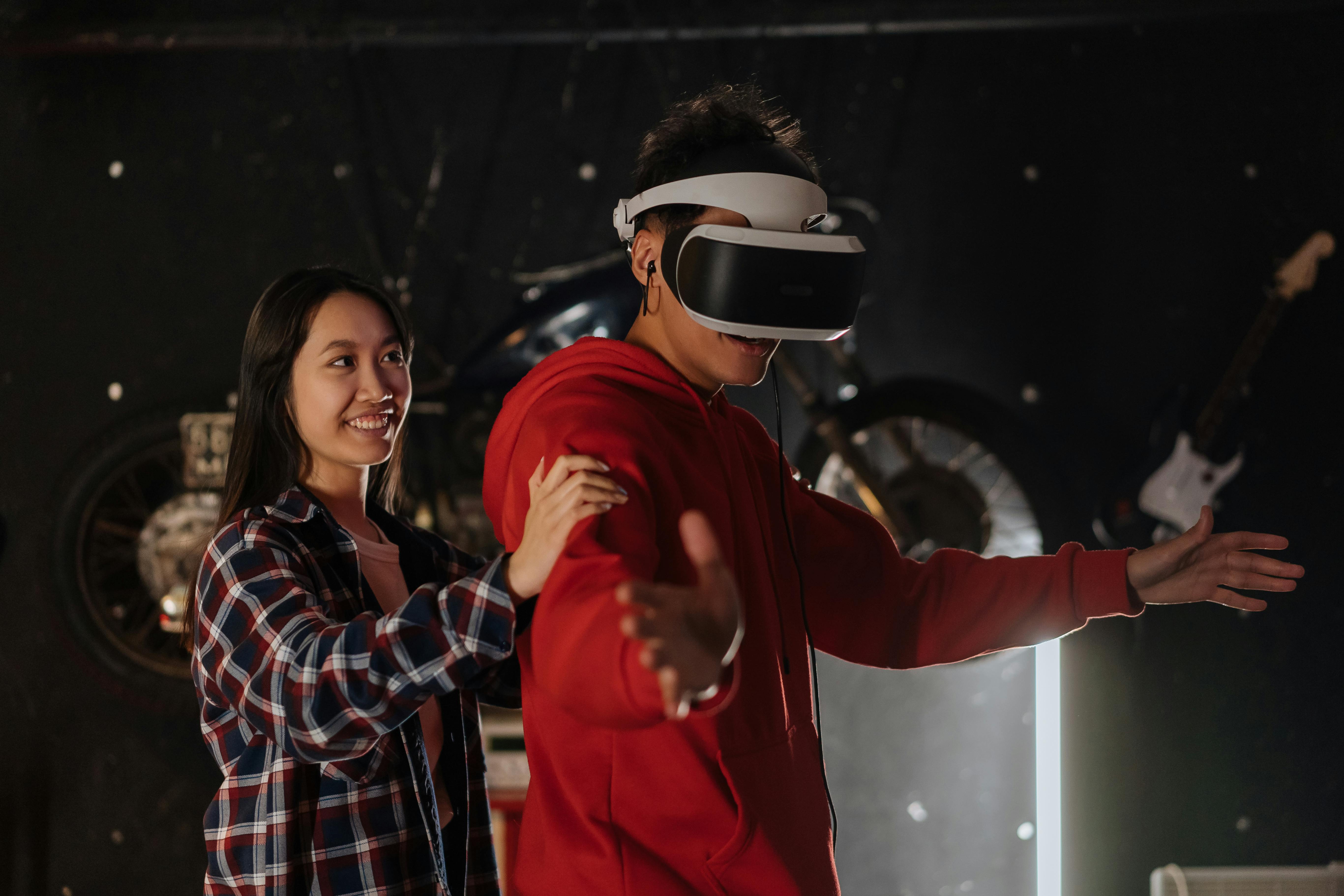 Free Young couple engaging in VR gaming indoors, wearing a virtual reality headset. Stock Photo