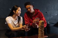 Two friends playing cards and Jenga indoors, sharing laughter and bonding over games.