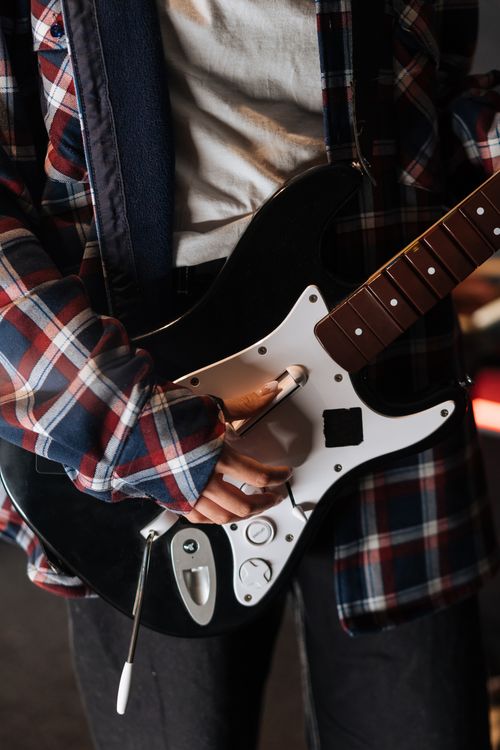Free Musician wearing flannel shirt playing electric guitar close-up indoors. Stock Photo