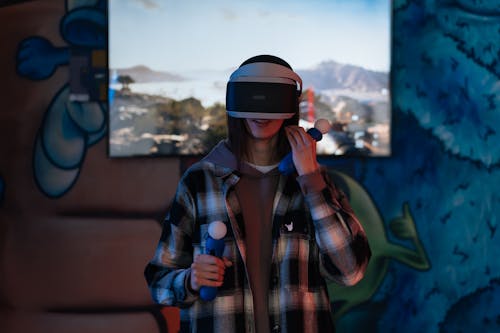 Young Woman Wearing VR Goggles and Holding Game Controllers
