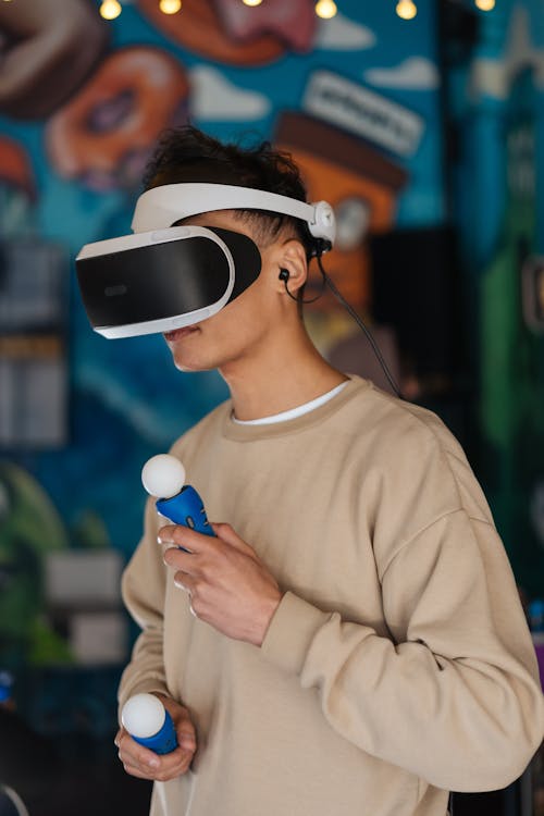 Man Wearing Virtual Reality Headset With Game Controllers On Hands