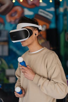 A young man wearing VR goggles and holding controllers, immersed in virtual reality gaming indoors.