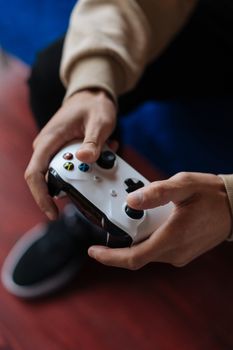 A close-up of a person holding a wireless game controller while gaming indoors.