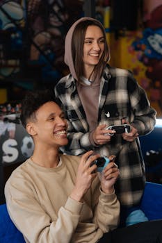 Two young adults playing video games with controllers, having fun indoors.