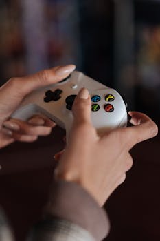Detailed shot of a person holding a video game controller, capturing vibrant buttons and elegant nail polish.