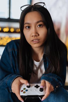 Asian woman with eyeglasses playing video game indoors.