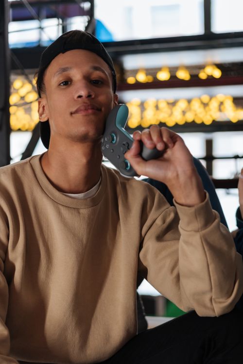Free A stylish young man in a beige sweater holding a game controller indoors. Stock Photo