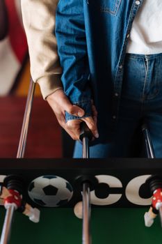 A close-up of a couple playing foosball, symbolizing love and intimacy through joined hands.