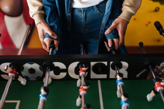 Hands on foosball rods, engaging in a lively indoor game.