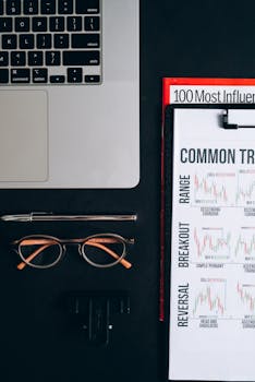Organized workspace with laptop, graphs, pen, eyeglasses on a black surface. Perfect for business concepts.