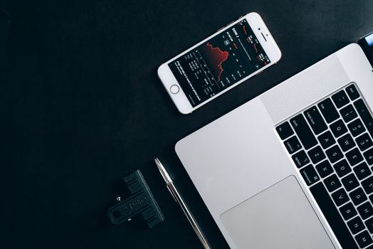 Modern workstation setup showcasing laptop, smartphone, and financial data for business use.