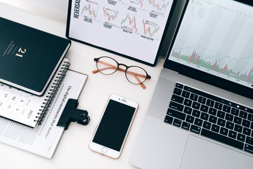 Free Organized workspace featuring laptop, smartphone, and graphs displaying financial data. Stock Photo