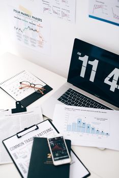 A neat desk setup with a laptop, phone, and financial documents, highlighting digital currency trends.