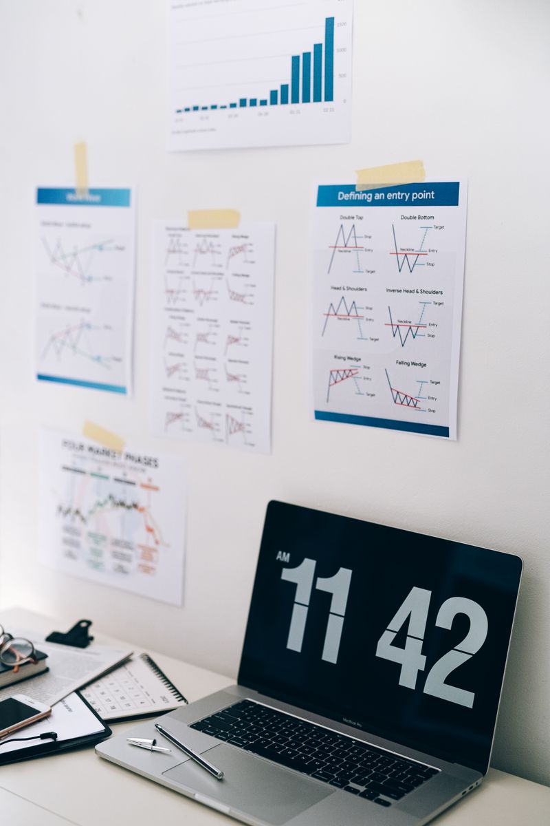 Office desk with financial charts on wall and a laptop displaying time, ideal for business themes.