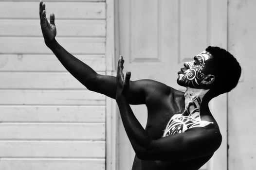 Striking black and white portrait of a dancer with intricate body art posing gracefully.