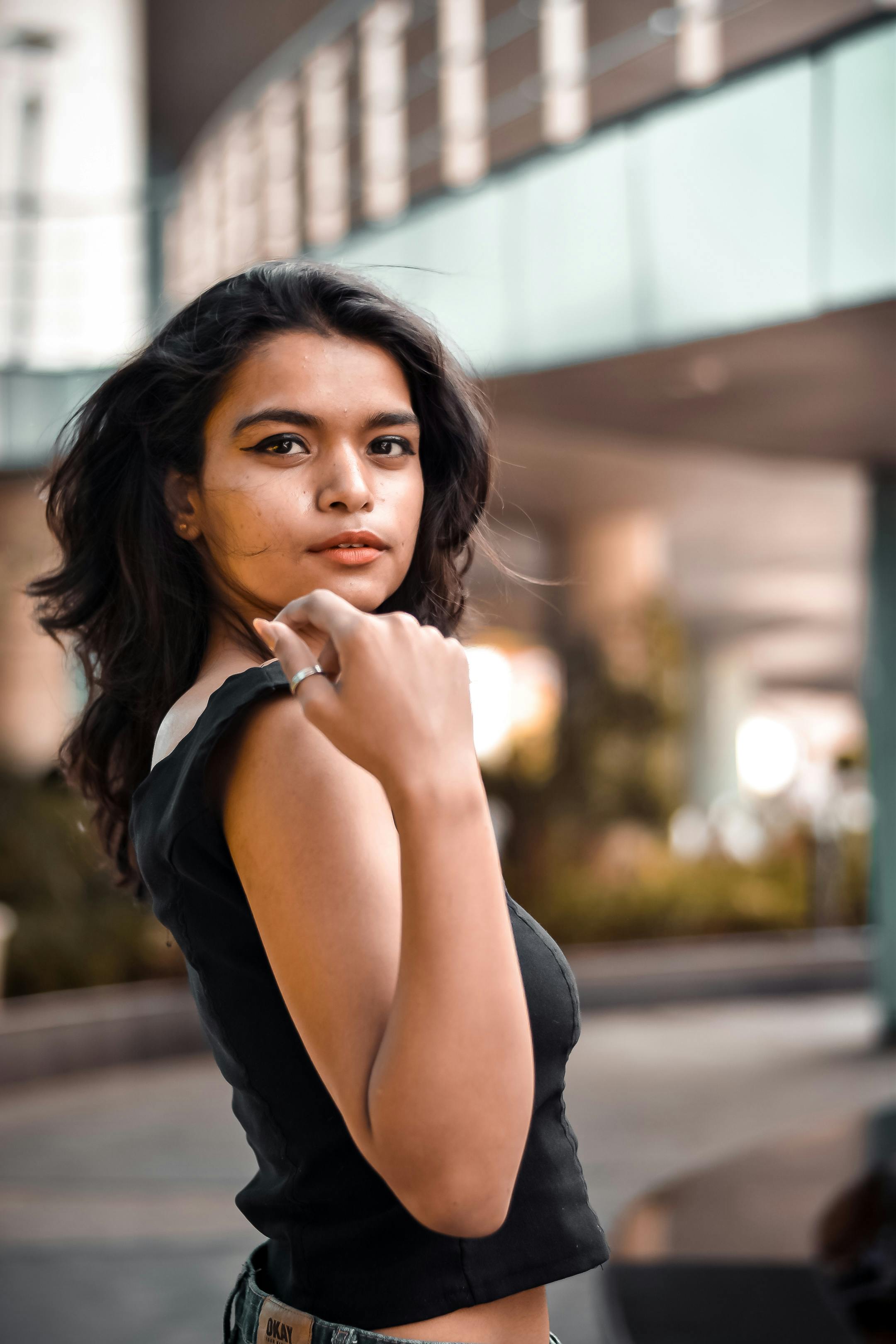 Elegant woman posing in a modern urban environment with natural lighting.